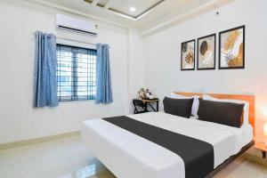 a white bedroom with a large bed and a window at Super Townhouse Kokapet Near GAR in Hyderabad