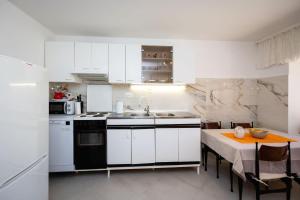 a kitchen with white cabinets and a sink and a table at House Zeljka in Podstrana