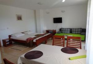 a room with two beds and a table and chairs at Apartments Vlado in Njivice