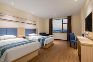 a hotel room with two beds and a desk at JTOUR Inn Xiantao Shopping Mall Pedestrian Street in Xiantao +234 photos