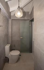 a bathroom with a toilet and a chandelier at ZANTE STARLET - Chic Hideaway with Pool & Comfort in Lagópodhon +9 photos