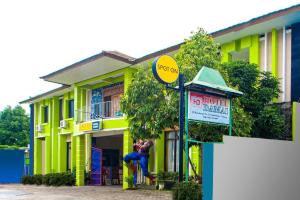 un bâtiment jaune avec un panneau devant lui dans l'établissement SPOT ON 2815 Hotel Damai, à Cilacap