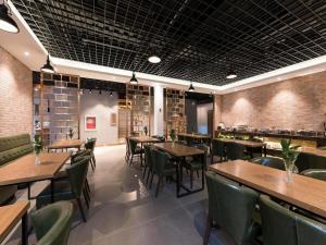 un restaurant avec des tables en bois et des chaises vertes dans l'établissement James Joyce Coffetel Beijing Pinggu Hospital Century Square, à Yuegezhuang