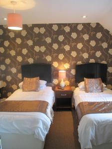 dwa łóżka w pokoju z kwiatami na ścianie w obiekcie The Astor w mieście Ballybunion