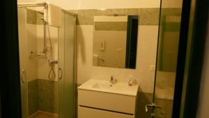 un bagno con lavandino e doccia con specchio di Affitta camere ALMA MATER a Castrignano del Capo