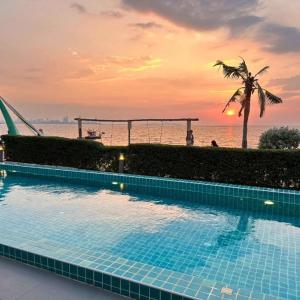 a swimming pool with a palm tree and the ocean at Golden Dragon Beach Resort Pattaya (Bang Lamung) in Ban Rong Po