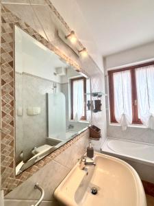 a bathroom with a sink and a tub and a mirror at Nura's - Casa Marirò in Alghero