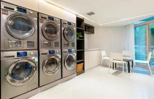 Un lavadero con varias lavadoras y una mesa y sillas. en ZTE Hotel Shenzhen, en Shenzhen