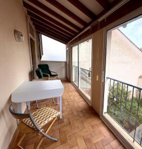 una stanza con tavolo, sedie e balcone di Appartement LE BOULOU 2 chambres a Le Boulou