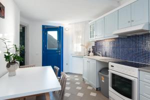 a kitchen with white cabinets and a blue door at Rocks and Waves Sifnos in Kamares