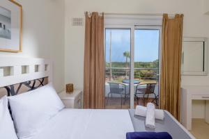 a bedroom with a bed and a balcony with a table at Aloni Grove Retreat in Chania