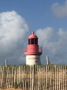 サン・ピエール・ドレロンにあるPort La Cotinière 100m plage et commercesの柵の向こうにある赤と白の灯台