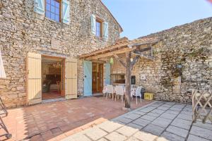 a stone building with a patio with a table and chairs at La Mijotière - maison avec piscine et grand jardin in Thénac