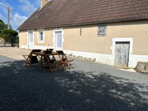 une table et des chaises devant un bâtiment dans l'établissement Maison de campagne rénovée, à Montaron