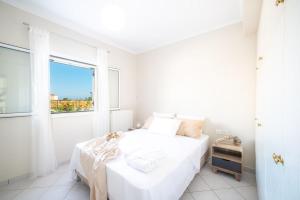 a white bedroom with a bed and a window at Villa Du Vignoble in Zakynthos Town