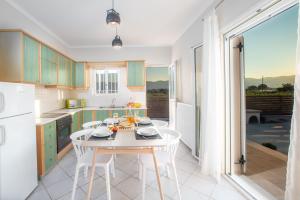 a kitchen with a white table and white chairs at Villa Du Vignoble in Zakynthos Town