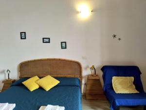 a bedroom with a bed with blue sheets and yellow pillows at Bilocale in centro con vista mare in Porto Santo Stefano