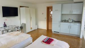 a room with a bed and a kitchen with white cabinets at G.O.D. Ferienwohnung in Bad Mergentheim