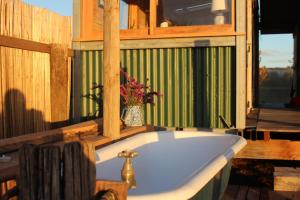 a bathroom with a tub with a vase of flowers at Freefall Cottage in Haumoana +10 photos
