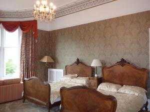 a bedroom with two beds and a chandelier at Moorlands in Helensburgh