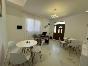 Habitación con mesas, sillas blancas y ordenador portátil. en Sofia Central House Berat, en Berat