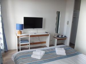 a bedroom with a bed and a desk with a television at Hôtel L'Océane in Andernos-les-Bains