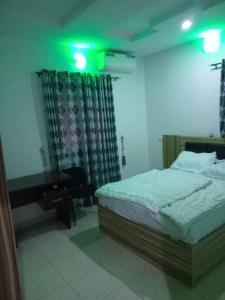 a bedroom with a bed and a desk and green lights at Molayo Luxury Apartment Omolayo Estates Akobo Ojurin Ibadan in Ibadan
