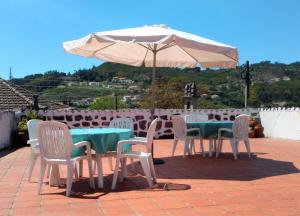 una mesa, sillas y una sombrilla en el patio en Quinta da Cumieira, en Cumieira