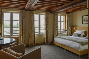 a bedroom with a bed and a table and windows at L'Absinthe Hôtel in Honfleur