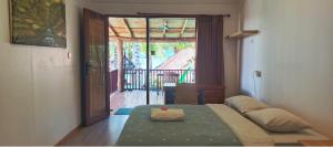 a bedroom with a bed and a door to a patio at Castaway Surf Retreat in Sekongkang