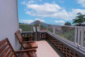 a balcony with two benches and a view of a mountain at Aurora Holiday House Kintamani in Kintamani