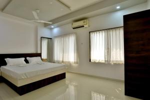 NavsāriHotel Sai Navsari的一间卧室设有一张床和两个窗户。