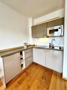 eine Küche mit Küchengeräten aus Edelstahl und Holzböden in der Unterkunft Balkon und Eleganz Düsseldorf in Düsseldorf
