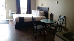 a hotel room with a bed and a table and chairs at Chinook Country Inn in Sundre