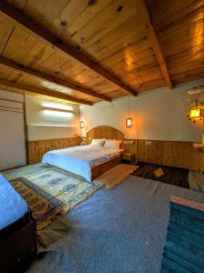 a large bedroom with two beds and wooden ceilings at The heavens place wooden room in Nagar