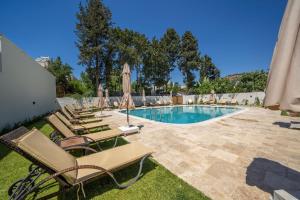 a swimming pool with lounge chairs and umbrellas at Olive Tree Hotel in Bodrum City