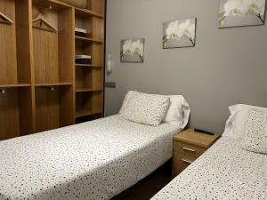 a bedroom with two beds and a wooden cabinet at Apartamentos Tajamar in Lastres