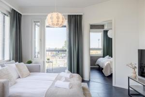 a white living room with a white couch and a bed at Calm Suite with Sauna and Free Parking - Heart of Lapland in Rovaniemi