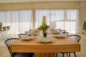 Una mesa de madera con platos y copas de vino encima. en YalaRent incredible Penthouses with all over sea view, en Eilat