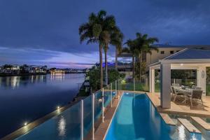 a house with a swimming pool next to the water at Stunning Waterfront Coastal Retreat, sleeps 13 in Twin Waters