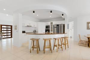 a kitchen with white walls and wooden stools at Stunning Waterfront Coastal Retreat, sleeps 13 in Twin Waters