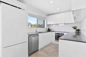 a white kitchen with white appliances and a window at Coastal 3BR Beachside Haven, Pet-Friendly! in Buddina +21 photos