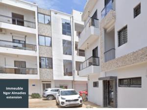 a building with a car parked in a parking lot at Aksil Jaam in Dakar