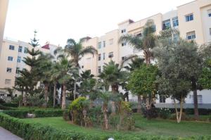 un bâtiment avec des palmiers devant dans l'établissement réside, à Oulad Akkou