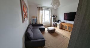 a living room with a couch and a flat screen tv at Charmante maison de ville lumineuse avec piscine in Vannes