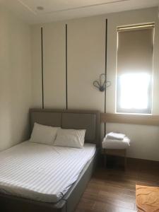 a small bedroom with a bed with a window at Khách Sạn Bách Thư Tây Ninh in Tây Ninh