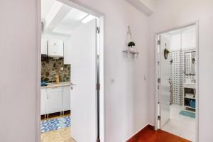 a kitchen with white walls and a door leading into a hallway at Casa Amarela in Tavira +24 photos