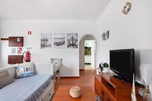 a living room with a bed and a tv at Casa Amarela in Tavira