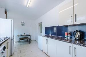 a kitchen with white cabinets and a blue accent wall at Stylish 3 bed house sleeps 5 free parking in Dudley Hill