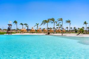 a swimming pool with palm trees and a beach at Villa Almendro Santa Rosalia Lake and Life Resort by PREMIUM SPAIN PROPERTIES in Torre-Pacheco